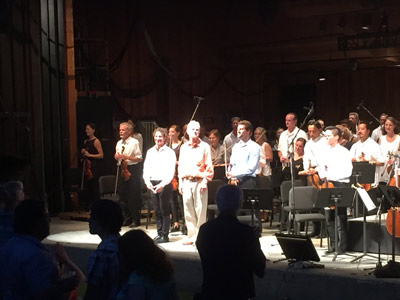 Composer John Adams, with Maestro Teddy Abrams, members of the Dover Quartet, and the Britt Orchestra, soak up the audience’s sustained applause after the performance of Mr. Adams’ Absolute Jest at the Britt Pavilion in Jacksonville, OR on Aug. 1, 2015.