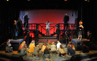 Jesus Christ (Erik Connelly) being crucified, between Caiaphas (Don Matthews) standing left and Annas (Michael Wing) standing right, with onlooking Roman Centurions (in storm trooper attire) and Jewish mob, in Camelot Theatre’s Jesus Christ Superstar. Photo by Steve Sutfin.
