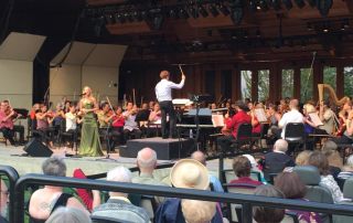 Guest singer Morgan James singing at the microphone and Music Director Teddy Abrams at the podium directing the Britt Orchestra for the performance of Something’s Coming from Leonard Bernstein’s West Side Story on August 9, 2015 in Jacksonville, OR.