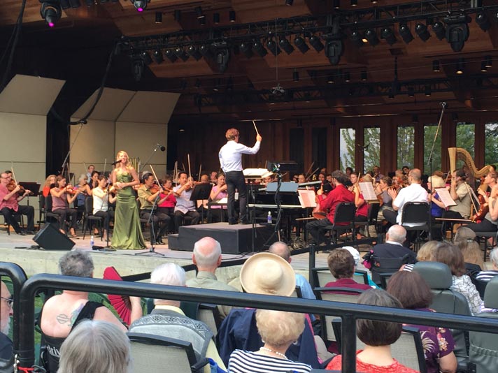 Guest singer Morgan James singing at the microphone and Music Director Teddy Abrams at the podium directing the Britt Orchestra for the performance of Something’s Coming from Leonard Bernstein’s West Side Story on August 9, 2015 in Jacksonville, OR.